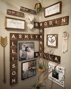 a wall with many frames and pictures hanging on the wall next to a vase filled with flowers