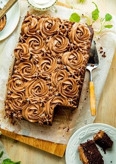 a chocolate cake with swirly frosting sitting on top of a wooden cutting board