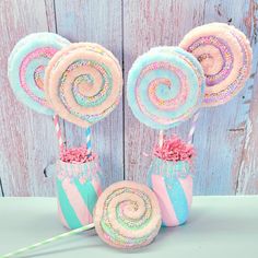 some lollipops are on sticks with sprinkles and pink flowers