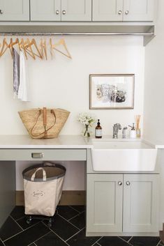 a laundry room with white cabinets and black tile flooring