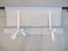 a white and blue striped towel hanging on a rail with two ties attached to it