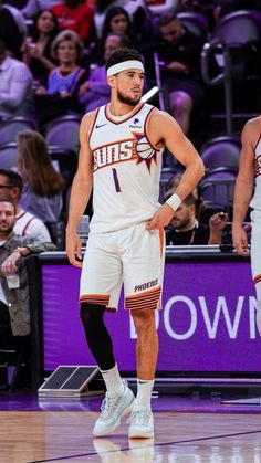 two basketball players standing on the court with their hands in their pockets and looking at something