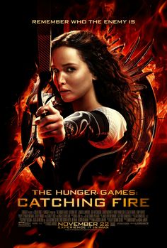 the poster for the movie's upcoming film, catching fire is displayed on a brick wall