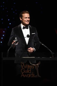 a man in a tuxedo standing at a podium with an award on it