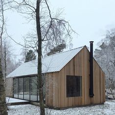 a small wooden house in the middle of winter with snow on the ground and trees