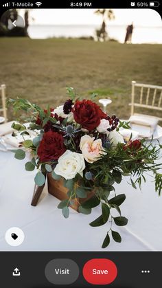 a vase filled with red and white flowers sitting on top of a table next to a chair