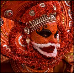 an elaborately decorated mask with red flowers around it