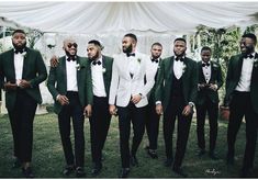 a group of men standing next to each other wearing green tuxedo jackets and bow ties