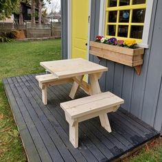 two picnic tables sitting on top of a wooden platform next to a yellow door and window