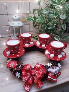 a christmas wreath made out of red cups and saucers on a table with candles