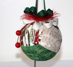 a christmas ornament hanging on a pole with red and green ribbon around it