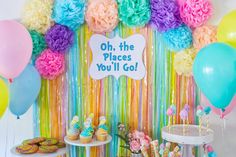 there is a colorful backdrop with balloons and desserts on the table for an oh, the places you'll go party