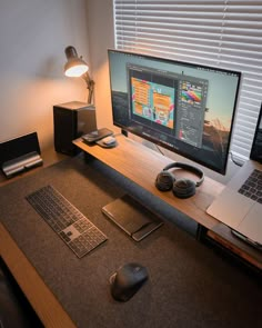 a computer desk with a laptop, mouse and keyboard on it next to a window