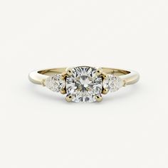 a three stone engagement ring with an oval diamond center and side stones in yellow gold