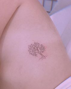 a small tree tattoo on the back of a woman's shoulder