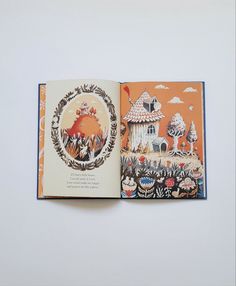 an open children's book with pictures of houses and animals in it on a white surface