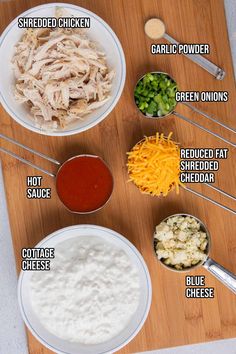 ingredients to make chicken salad laid out on a cutting board, including shredded cheese, green onions, grated cheese and sauce