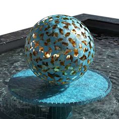 a large metal ball sitting on top of a blue table next to a swimming pool