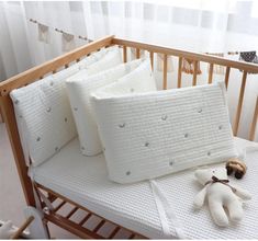 a baby crib with three pillows and a stuffed animal