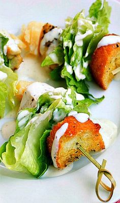 small appetizers with lettuce and dressing on a white plate