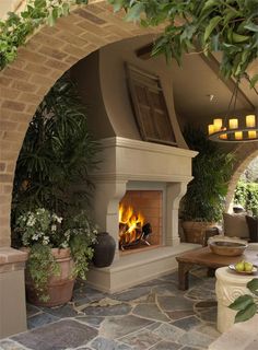 an outdoor fireplace with potted plants and candles