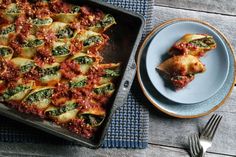 a casserole dish with spinach, cheese and tomato sauce on a blue plate next to a fork