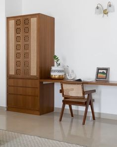 a wooden cabinet sitting next to a desk with a plant on it's top