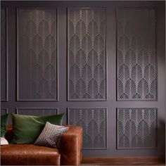 a brown leather couch sitting in front of a wall with decorative paneling on it