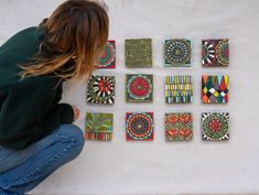 a woman sitting on the ground next to some colorful tile pieces that look like they are made from wood