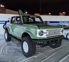 a green pick up truck parked on top of a tarp