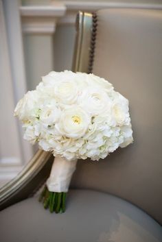 a bouquet of white flowers sitting on top of a gray chair next to a mirror