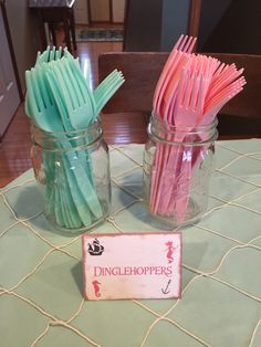 two mason jars filled with pink and blue toothbrushes on top of a table