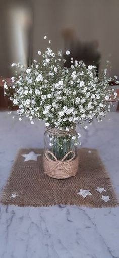 a vase filled with white flowers sitting on top of a table next to a burlock