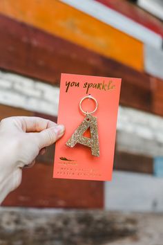 a person holding up a card with the letter a on it and a keychain attached to it