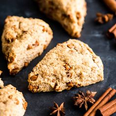 some cookies and cinnamon sticks are on a black surface with anisette, star anise