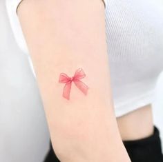 a woman's arm with a red bow tattoo on it