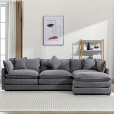 a living room with a large gray sectional couch and white rugs on the floor