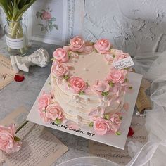 a wedding cake with pink flowers on it and two small vases next to it