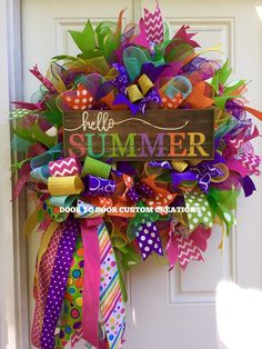 a colorful wreath with the words hello summer hanging on a white front door decorated with ribbons