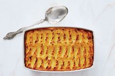 a square casserole dish on a marble countertop with a spoon next to it