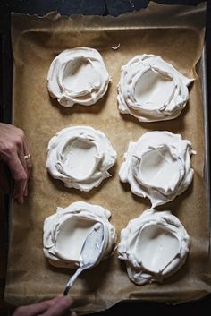 someone is spreading icing on top of cupcakes in the shape of flowers