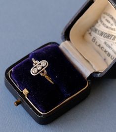 an open ring in a velvet box on top of a blue tablecloth covered surface