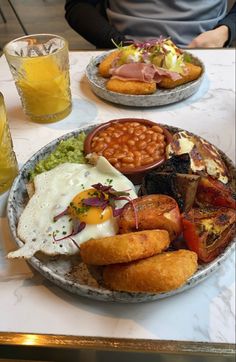 two plates filled with different types of food on a table next to glasses and drinks