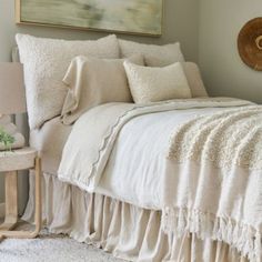 a bed with white linens and pillows in a bedroom next to a painting on the wall