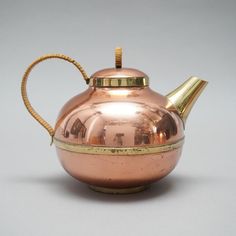 a shiny metal tea pot with a golden handle