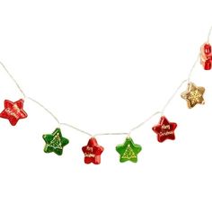 christmas lights are hanging on a white wall with red, green and gold stars attached to them