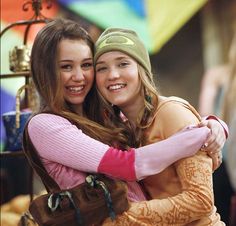 two young women hugging each other in front of colorful umbrellas at an amusement park