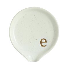 a white plate with an e on the side and a gold letter in the middle