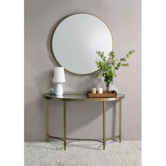 a round mirror sitting on top of a table next to a vase with flowers in it