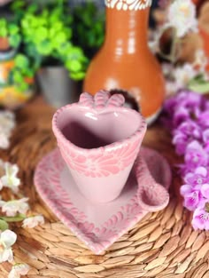 a pink cup and saucer sitting on top of a wicker basket next to flowers